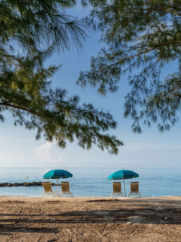 Photo of two beach chair and umbrella set ups on the beach at Fort Zachary Taylor Park.