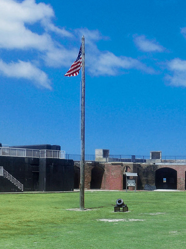 Photo of the American flag and cannon in the middle of the Fort Zachary Taylor courtyard.