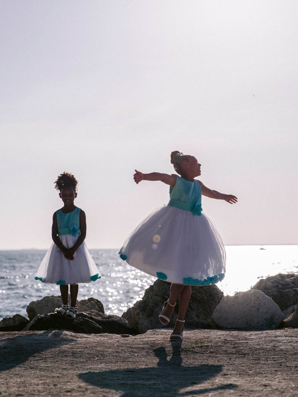 photo of two young girls dancing in dresses at the beach.